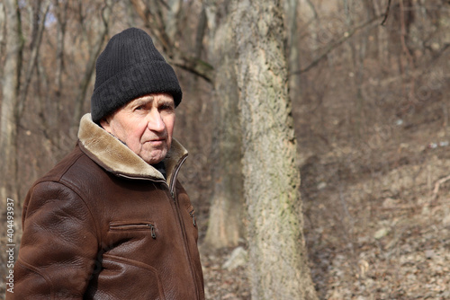Portrait of elderly man standing in winter forest. Concept of old age, life in village
