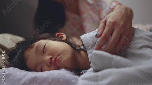 Asian mother tuck in blanket her cute kid on the bed. Concept for mom goodnight daughter. 4K Video slow motion.