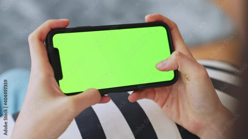 Young Asian woman holding in hands a mock up smartphone with green
