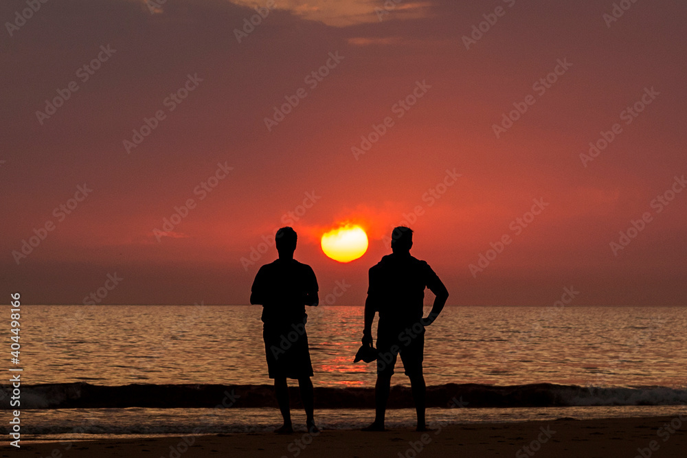 Silueta de dos hombres contemplando el atardecer en la playa de Los Lances, Tarifa, Provincia de Cádiz, Andalucía, España Silueta de dos hombres contemplando el atardecer en la playa de Los Lances, Tarifa, Provincia de Cádiz, Andalucía, España