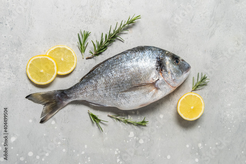 Fresh fish dorado or sea bream  with lemon on stone table with ingredients for cooking  flat lay composition . Healthy food concept. Top view with copy space.