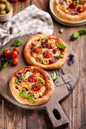 Mini Pizza with tomatoes, chicken, red onion, olives and mozzarella cheese. Delicious homemade pizzetta. Italian cuisine. #404499591