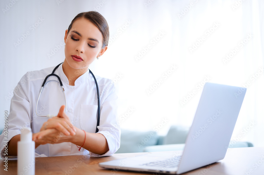 Young female doctor applies antiseptic gel before start working day. Hospital worker cleaning hands using liquid alcoholic sanitizer Young female doctor applies antiseptic gel before start working day. Hospital worker cleaning hands using liquid alcoholic sanitizer