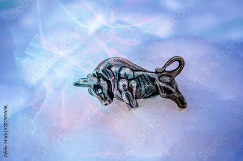 Soft focus. Bull symbol of the year 2021. Year of the white metal bull according to the Chinese calendar. Souvenir bull made of silver metal on a snow background with bokeh effect. High quality photo