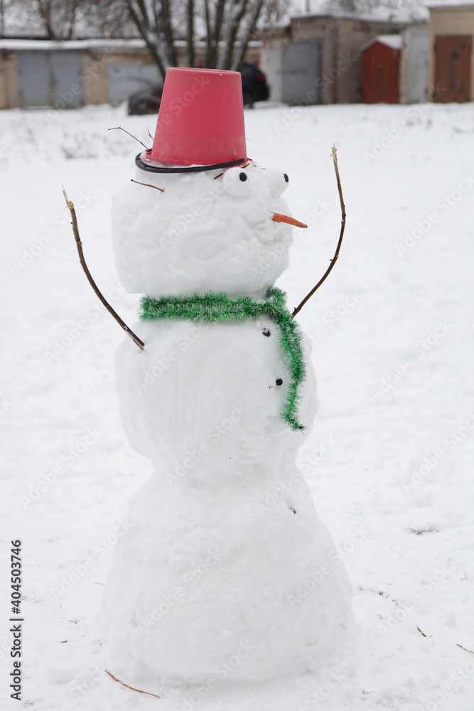 Φωτογραφία One funny cute snowman with bulging eyes, green scarf and red bucket hat on his