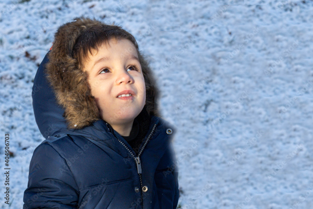portrait of a little boy looking at the sky sheltered for the cold winter portrait of a little boy looking at the sky sheltered for the cold winter