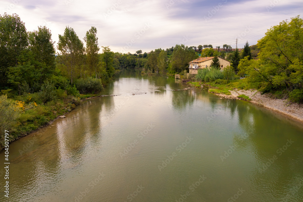 View of the river Ter as it passes through Sant Hipolito de Voltrega, where the trees that border it are reflected in its calm waters on a summer day. Catalonia, Spain