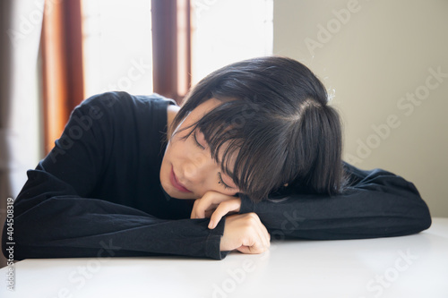 sleepy woman sleeping, taking nap in living room during winter day time, concept of tiredness, insomnia, sleeping disorder, relaxing asian girl