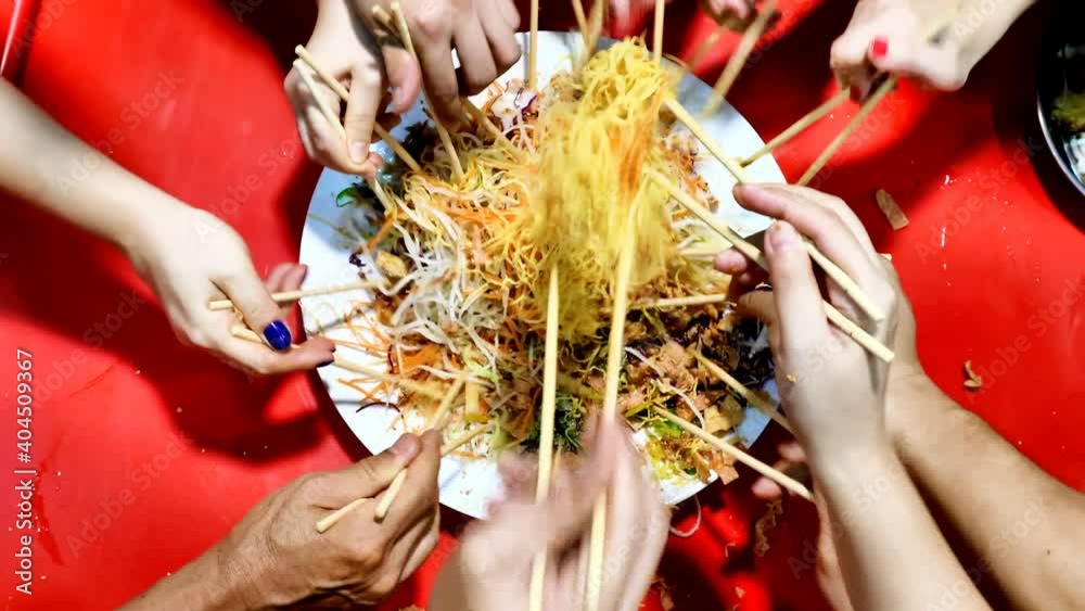 Close-up of people tossing yusheng or yee sang during Chinese New Year dinner celebration for good luck