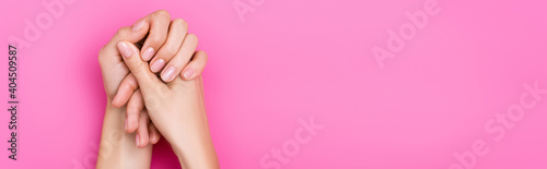top view of female hands with pastel manicure on pink background, banner
