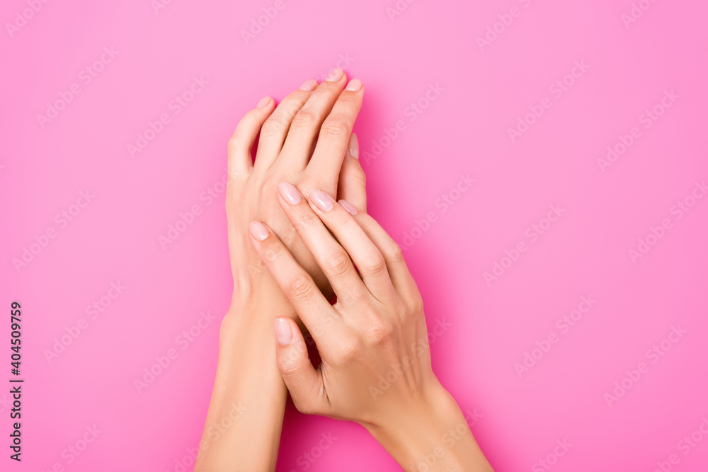 top view of groomed female hands with shiny fingernails on pink background