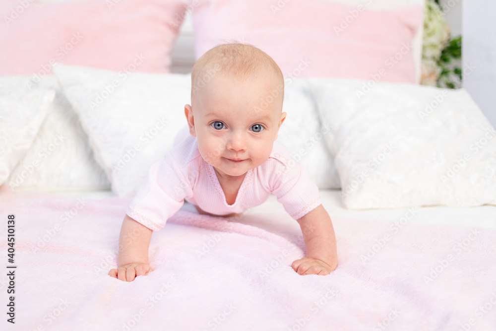 small baby girl 6 months old crawling on a white and pink bed at home, looking at the camera, place for text small baby girl 6 months old crawling on a white and pink bed at home, looking at the camera, place for text
