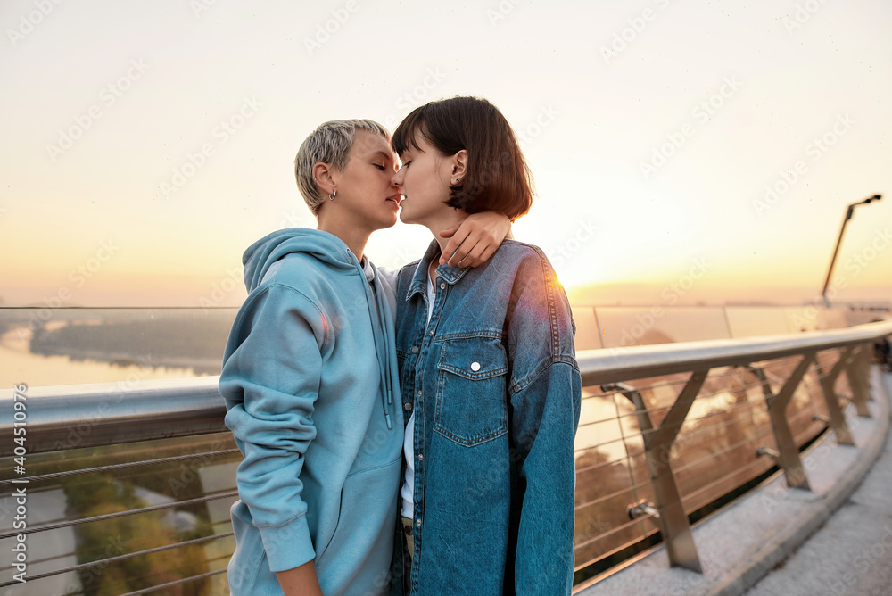Young passionate lesbian couple kissing outdoors, Two women enjoying romantic moments together at sunrise