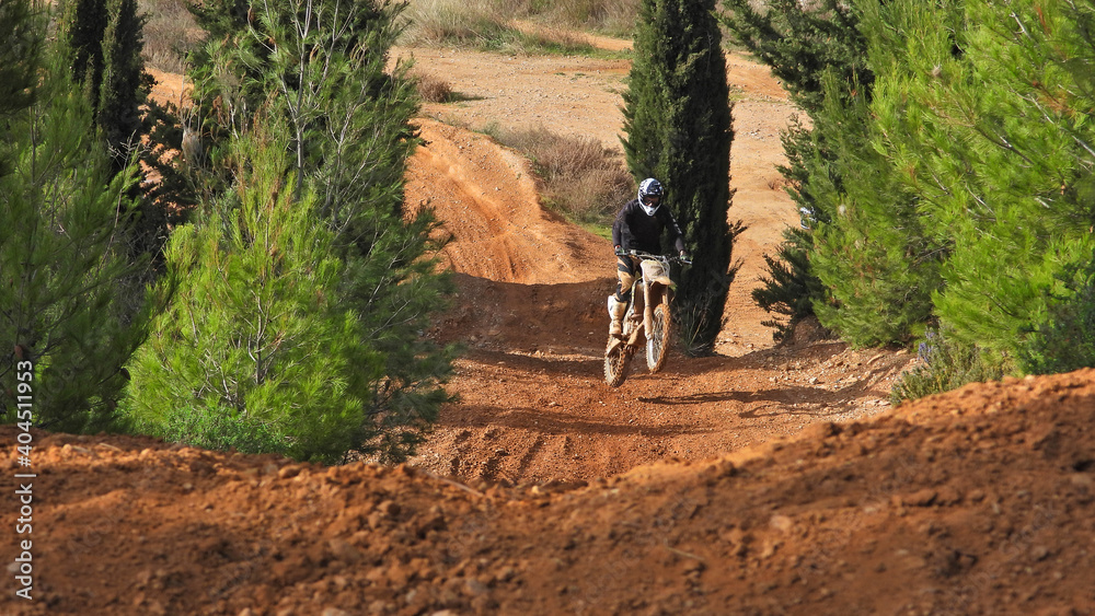 Zoom photo of motocross professional rider in action performing high speed flying stunts in dirt and mud terrain Zoom photo of motocross professional rider in action performing high speed flying stunts in dirt and mud terrain
