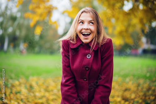 Portrait of happy blonde woman in park in autumn. She is enjoying nature.