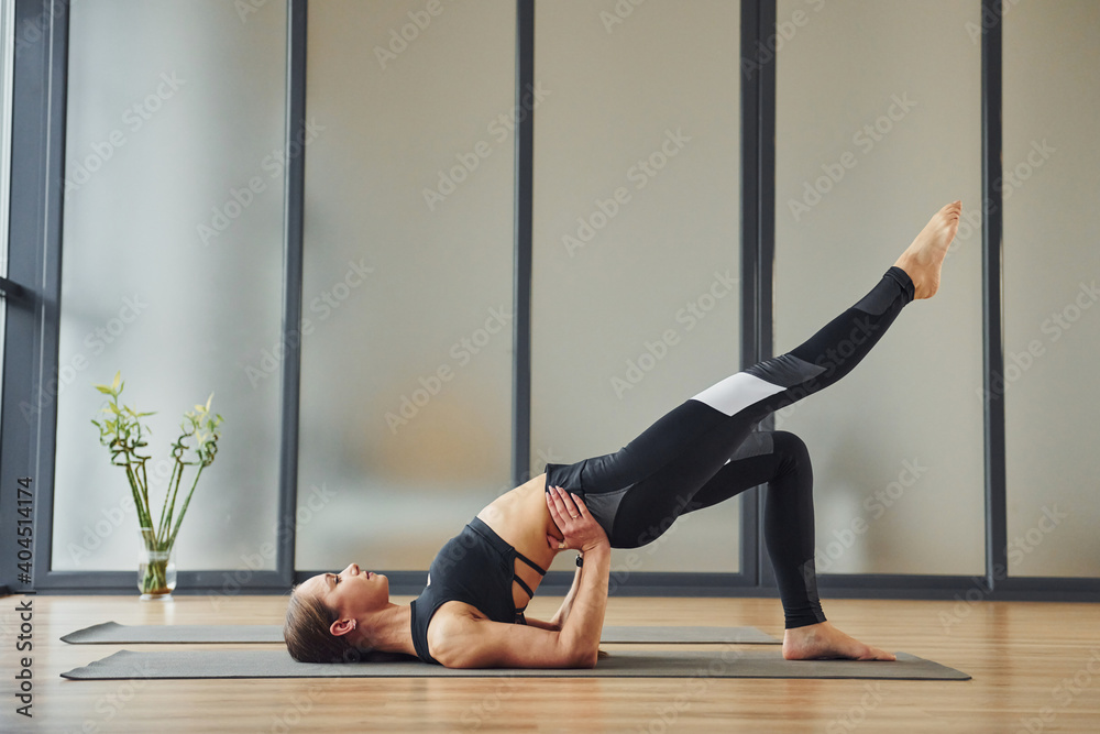 On the mat. Young woman in sportive wear and with slim body have fitness yoga day indoors