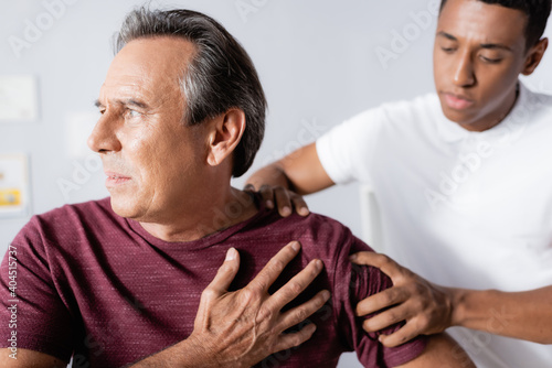 african american physiotherapist working with injured mature man in clinic