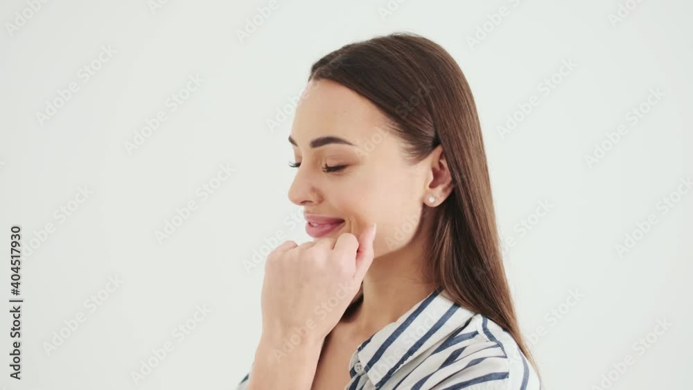 An attractive woman is posing to the camera standing isolated over white background in studio An attractive woman is posing to the camera standing isolated over white background in studio