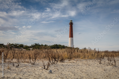 Barnegat Lighthouse, NJ, surrounded by sandy beach and golden wild grasses on a brisk winter day under blue cloudy sky photo