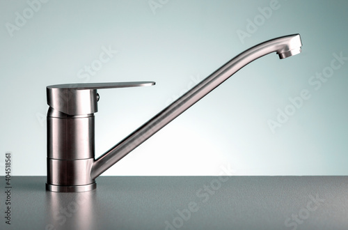 Close up of modern kitchen faucet on dark color countertop.