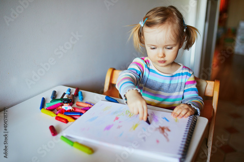 Adorable little girl painting with color pencils at home, in kindergaten or preschool photo