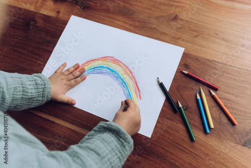 Kleinkind malt bunten Regenbogen mit Buntstiften photo