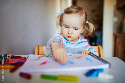 Adorable little girl painting with color pencils at home, in kindergaten or preschool