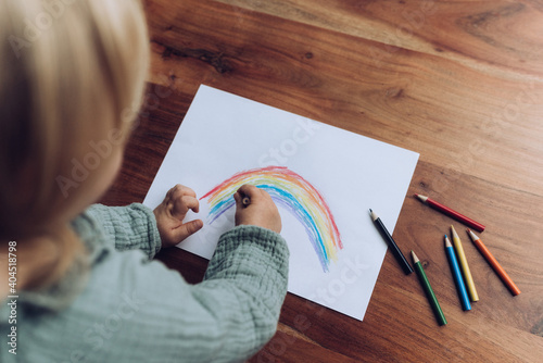 Fotografie Kleinkind malt bunten Regenbogen mit Buntstiften