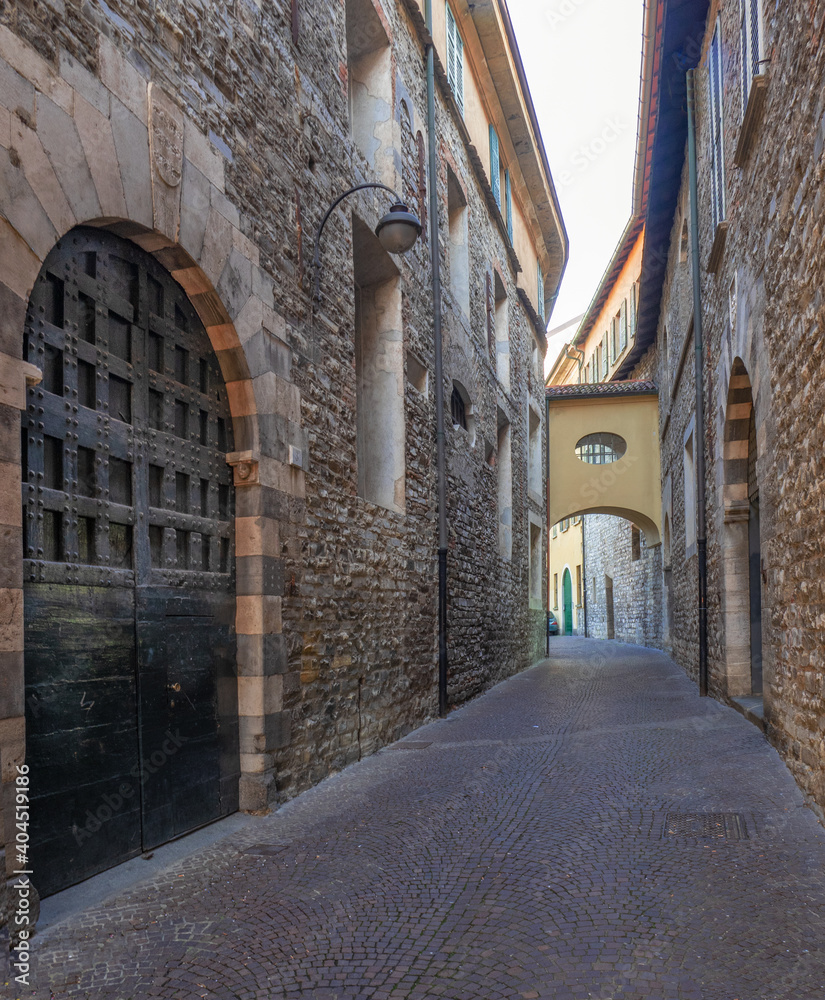 view along a medieval, dark and narrow alley with ancient stone houses.Como, Lombardy.Italy