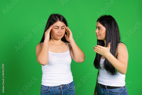 Emotional girls brunette on a green background in the same clothes. Fatigue and headache.