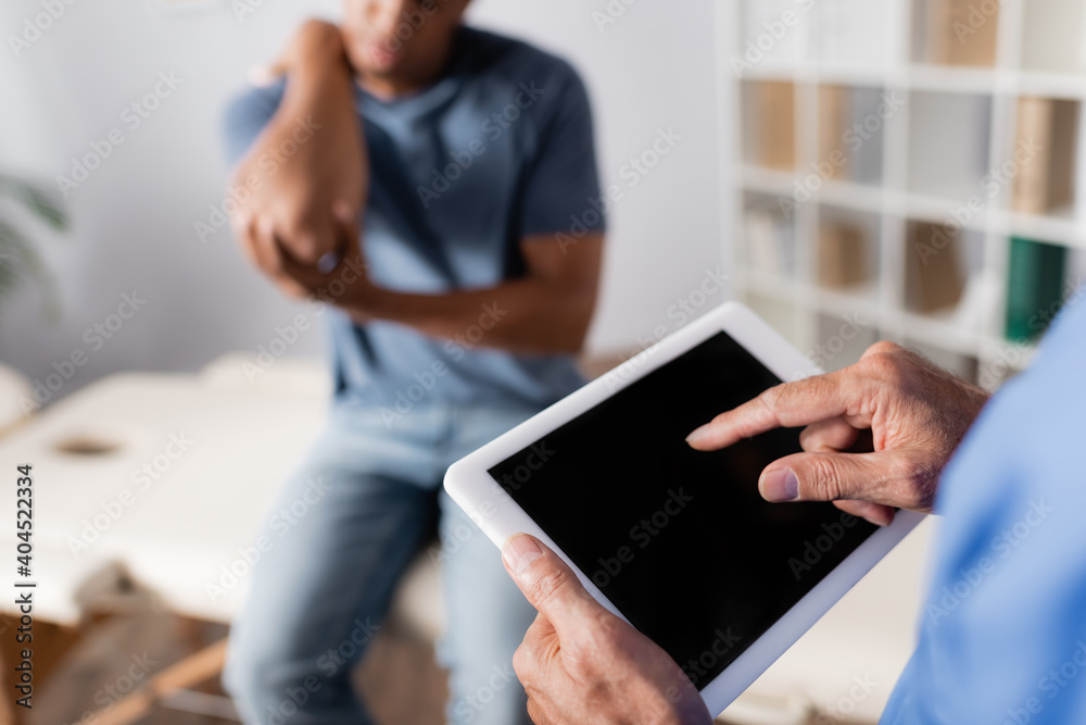 cropped view of doctor pointing with finger at digital tablet near african american patient on blurred background cropped view of doctor pointing with finger at digital tablet near african american patient on blurred background
