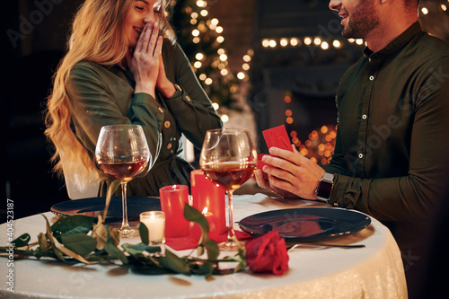 Man proposing a beautiful woman to marry him in an elegant restaurant. Young lovely couple have romantic dinner indoors together