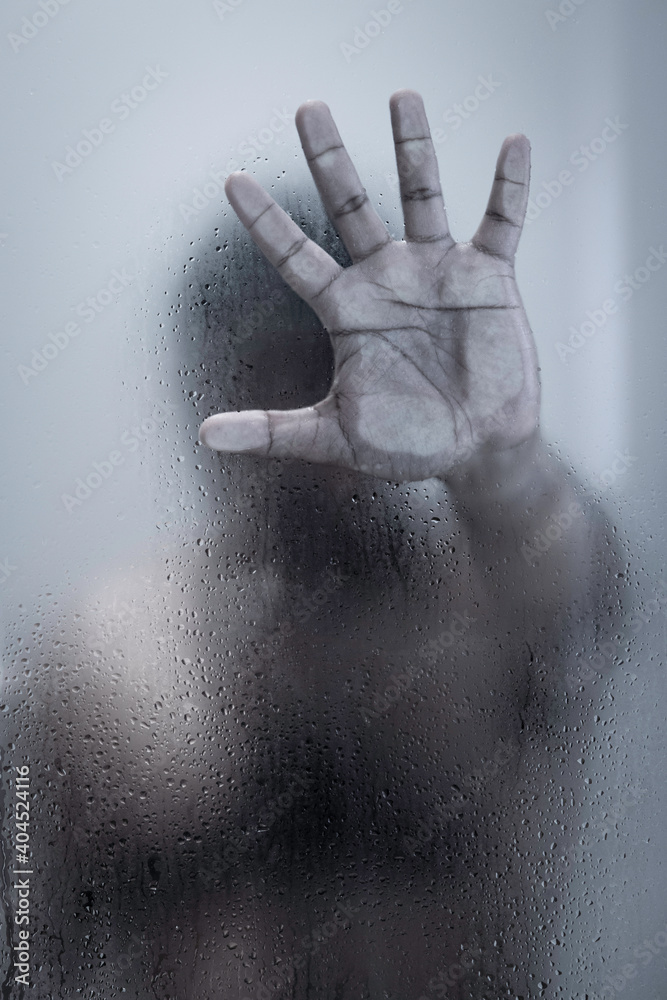 Fototapeta premium Photo of a man behind a foggy glass