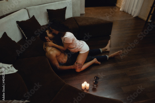 Enjoy the moment. Young sexy woman seducing man undressing him before having sex on the floor
