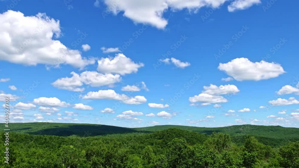 White clouds floating in the blue sky and mountain covered by forest, time-lapse