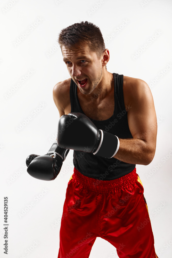 Aggressive boxer in black boxing gloves punching isolated on white background.