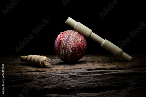 Cricket ball and bails still life close-up on a highly texture wooden surface. 