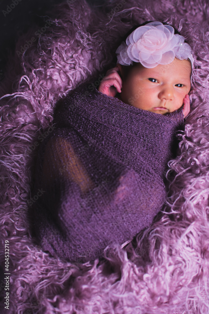Φωτογραφία Newborn baby girl in a purple outfit and background.