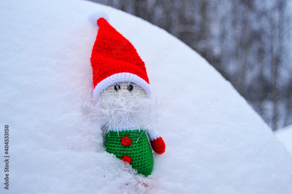 Toy gnome in red riding hood in the snow in winter Toy gnome in red riding hood in the snow in winter