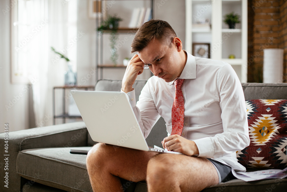 Businessman with no pants working at home. Young man using the laptop having video call.. Businessman with no pants working at home. Young man using the laptop having video call..