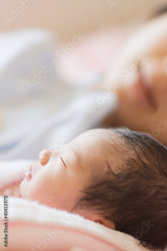 眠る新生児と見守る母親