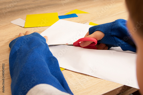 Closeup photography of the child cutting paper.Counterfeiting process.Concept of the home education.