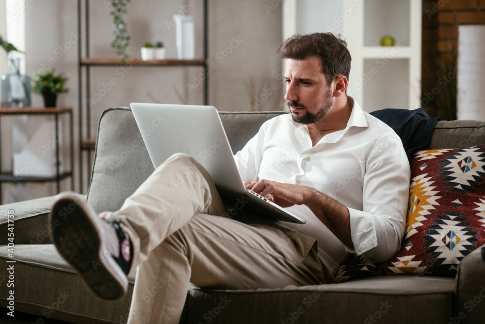 Young businessman working with laptop at office. Businessman sitting on sofa working on laptop computer..