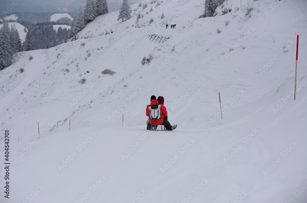 Hochgrat, Oberstaufen, Germany - January 08, 2021: couple on sleigh going down the mountain