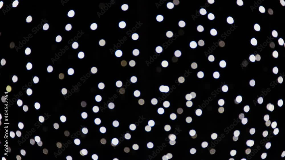 Abstract white blurred lights sparkling and glowing on black background. Christmas or New Year holiday concept