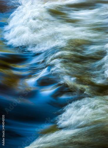 Close up abstract motion blue of waves in river with ripples colors and moving water