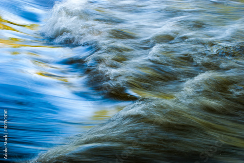 Close up abstract motion blue of waves in river with ripples colors and moving water