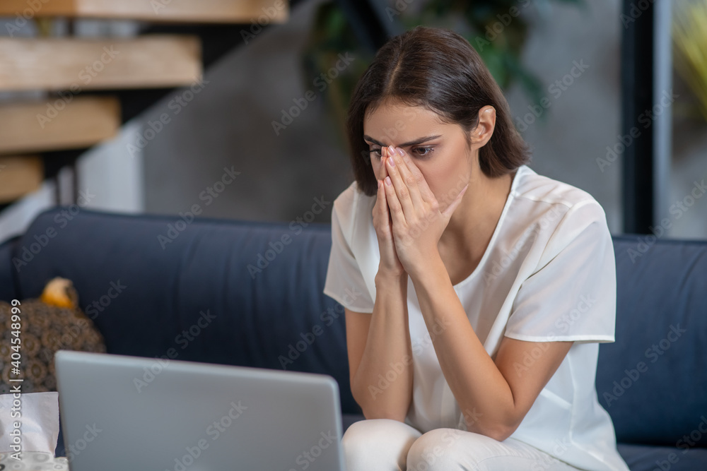 Sad and concentrated woman working with her laptop - obrazy, fototapety, plakaty 