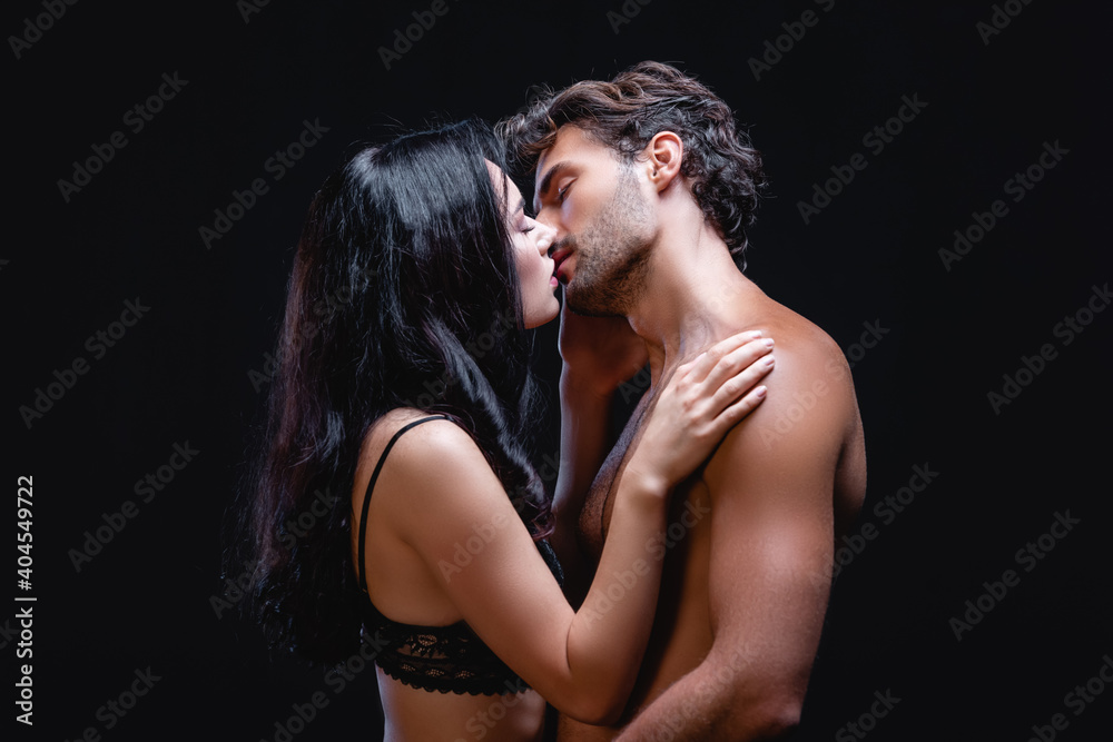 side view of seductive brunette woman kissing sexy shirtless man isolated on black side view of seductive brunette woman kissing sexy shirtless man isolated on black