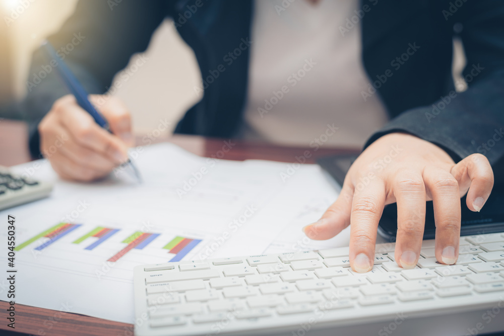 business woman hand using keyboard and typing computer technology for analysis and budget financial accounting with use pen pointing on growth statistics chart and graph on paper work. business woman hand using keyboard and typing computer technology for analysis and budget financial accounting with use pen pointing on growth statistics chart and graph on paper work.